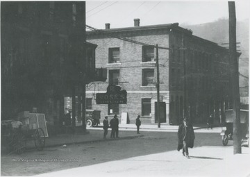 An unidentified man crosses the street. Rose's Drugstore pictured on the left.