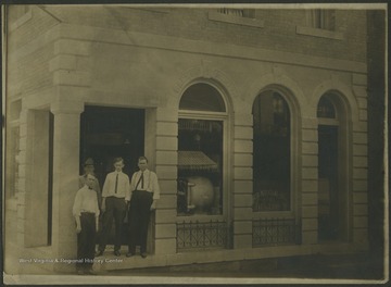 Four unidentified men pose by the entrance. The bank is located on the corner of 3rd Ave. and Temple St. 