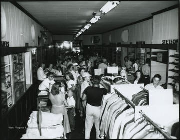 Interior of the store located on Temple St. A crowd of people shuffle through the store and examine the products for sale. Subjects unidentified. 