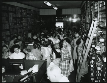 Interior of the store located on Temple St. A crowd looks through the store to examine products for sale. Subjects unidentified. 