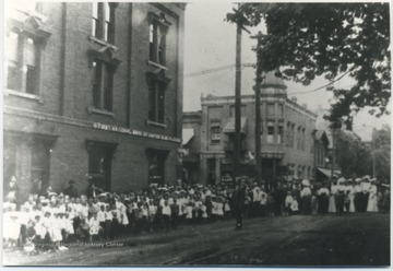 A crowd gathers on the street beside the First National Bank of Hinton building. Subjects unidentified. 
