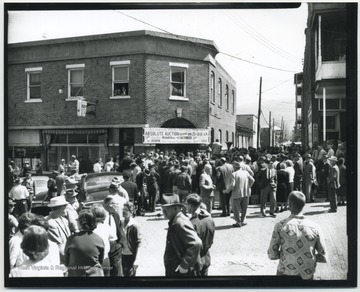 A crowd surrounds the building located on 3rd Avenue. The sign at the entrance reads, "Building and All Stock and Fixtures To Be Sold at Absolute Auction, Saturday at 10:00 a.m." Subjects unidentified. 