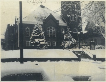 View of the snow covered church building and grounds from the street below.
