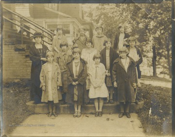 A Sunday School teacher poses with twelve young girls on the outside steps. Subjects unidentified. 