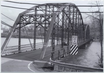 A car drives across the bridge that runs over Cheat Lake and along County Route 857.The bridge was built in 1922 by the Independent Bridge Company of Pittsburgh. 