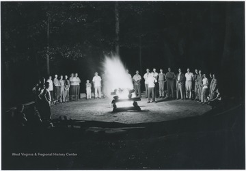 Campers and counselors gather around the campfire. Subjects unidentified. 