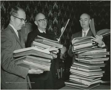 Emil Hudel, Editor of Beckley Post Herald; John Faulconer, Editor of Hinton Daily News, and Jim Comstock, Editor of The West Virginia Hillbilly examining the club's books.