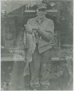 Goff, a fishing buddy of Edward Turner's, smiles with a large fish. Sports Mart sign pictured in the background. 