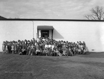 School children take a group photo outside of the school on a warm December day.