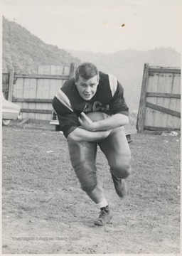 A football player at Hinton High School, Bennett is pictured in his team uniform running while cradling a football. 