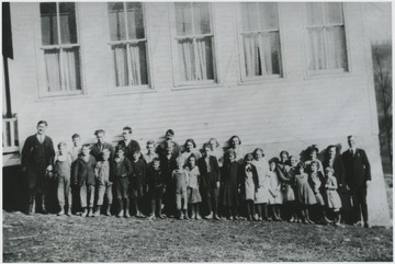 Students and teachers pose outside of the school building. Fifth from left is John Milburn.