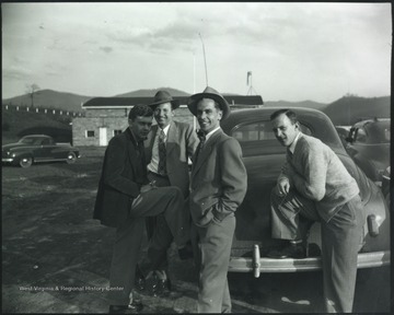 Charles Schrader, second from left, and Bill Meador, far right, pictured with two unidentified associates in the parking lot at the airport.