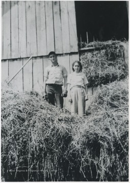 Freeman and Angell pictured standing on top a tall pile of hay. 