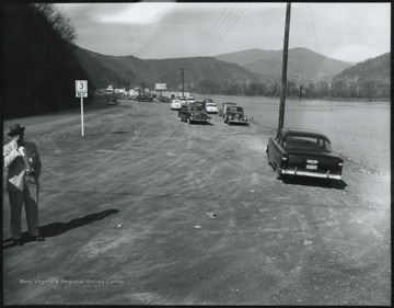 Automobiles line along the New River's shore line so their passengers may observe the view. 