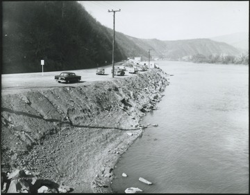 Automobiles line along the west side of the river so that their passengers can look out from the shore. 