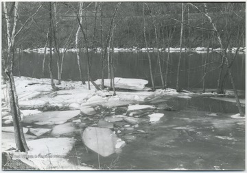 Ice blocks and snow cover the river banks.