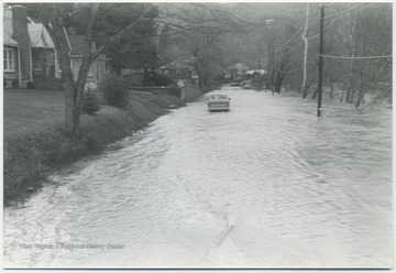 Flood waters from the Greenbrier River make driving difficult for the car pictured.