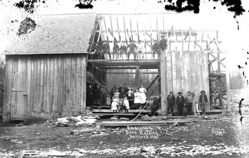 Group of people all over barn under construction.