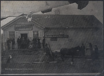 Pack family members pose in front of entrance of a building. An unidentified man is pictured in a horse-drawn carriage right outside the building. 