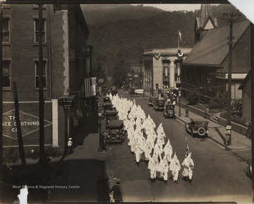 KKK members walk down 2nd Avenue between Ballengee and Temple Streets in their hoods and robes.