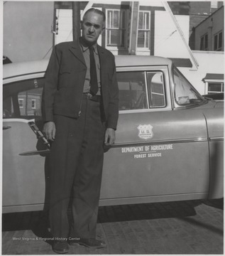 Keaton stands beside the U. S. Department of Agriculture's Forest Service automobile.Keaton was born June 13, 1913 and his father was L. B. Keaton, the former sheriff. G. E. Keaton married Elizabeth Kelly in 1935 and fathered two girls, Margaret and Elaine.