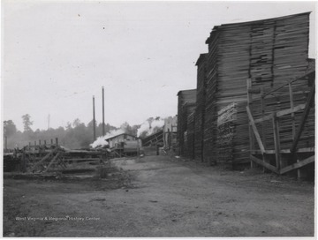 Stacks of lumber tower over a building in the background. 