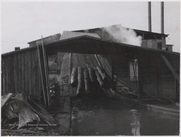 An unidentified employee watches as the logs are taken into the sawmill. 