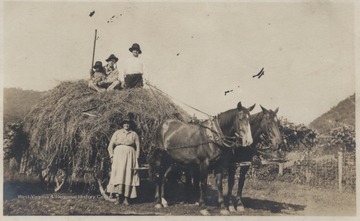 Fred Meador pictured on the right with Foy in center on top of the hay stack. Emma Meador is pictured on the ground next to the horse. 