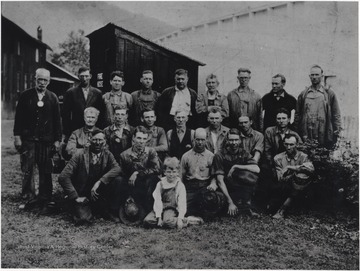 A group of men and one young boy stand in front of the C. & O. Fire Hose Station. O. P. Garten, husband of Ruby Garten, is third man from right in the back row. The remaining subjects are unidentified. 