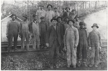 In the front row, from left to right, is Clarence E. Long, his brother-in-law H. W. Dodrill, unkown, and Elery C. Long, Clarence's brother.Second from left of the men on the tracks is Walker Jim Adams. The rest of the men are unidentified African-American men. 