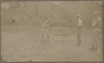 Herbert Swats pictured holding a baseball bat ready to swing while two unidentified men observe on the right. Swats is grandfather to David Ballard. 