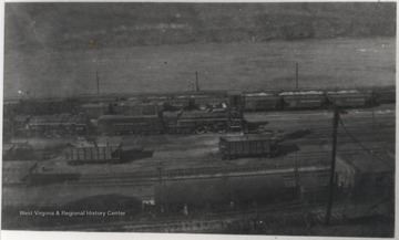 View overlooking train cars in the railroad yard beside a river. 