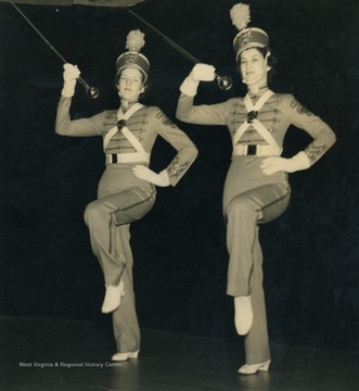 Caption accompanying photograph reads: "Erma Ellis and Mary Visnick are employed at the Martins Ferry Factory. When dressed in their uniforms these two comely drum majors lead the way when the Martins Ferry Band marches to the broadcast of "It's Wheeling Steel"."