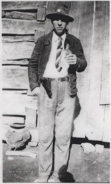 Lilly pictured with a hand gun strapped to his belt and bottle in his hand.