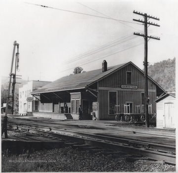 An unidentified man is pictured outside the C. & O. station. An Esso station is also pictured in the background.