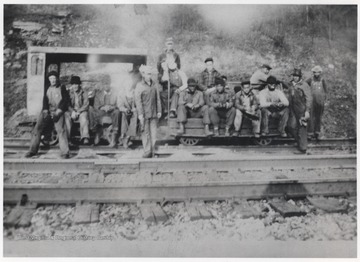 Pictured on the far left is Scott Owens (foreman). The rest of the workers are unidentified. The group is pictured on the railroad tracks with a smaller cart.