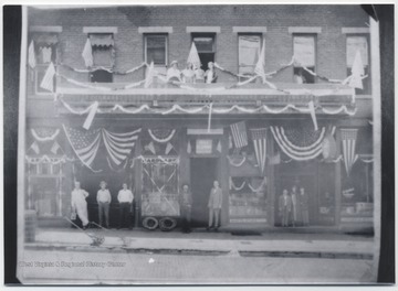 Unidentified people are lined up against the building, which is covered in American flags, located on the corner of Third Avenue and Temple Street.
