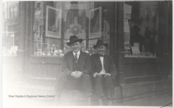 Two unidentified men sit on a step of the building which is located on the corner of Third Avenue and Temple Street.