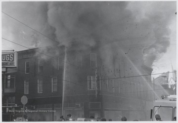 Smoke billows from the windows of the three-story, brick building originally built to house Rose's Drug Store, Co.