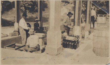 G. F. Miller pictured in the photo under the awning with unidentified associates. A spring runs directly next to the building and through the sitting area beneath the porch.