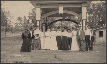 A group of unidentified persons pose in front of the awning that hovers over the running spring.