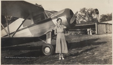 What is likely Gwinn poses next to an airplane.