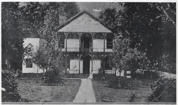 View looking a the entrance of the home. Four unidentified persons sit along the porch.