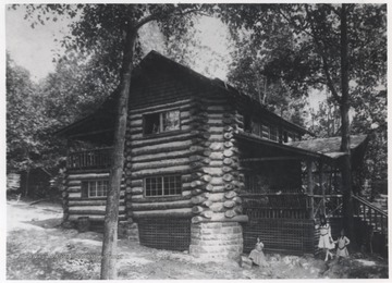 Three unidentified girls stand beside the grand log cabin.