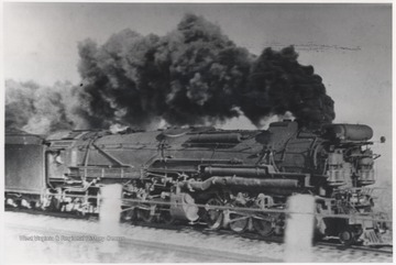 Smoke billow from the locomotive as it speeds across the tracks.