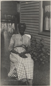 Kelly sits on a chair on a lawn.