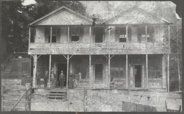 Five men and a woman stand on the porch of the inn.