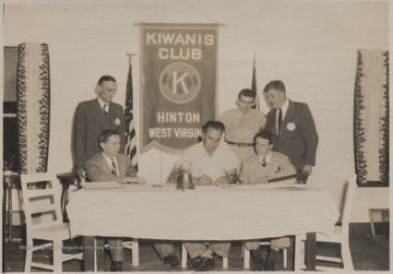 Ray Carter signing up his son and another boy from Bluefield, who enlisted in the United States Army through the Kiwanis Club. Bill Keyser, Sgt. Allen and Doc Graham are pictured standing.
