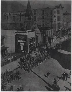 Uniformed men march down Temple Street as spectators watch from the sidewalks. 