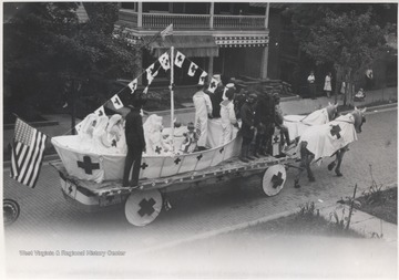 Uniformed soldiers and nurses sit in what appears to be a Red Cross parade float drawn by horses down Temple Street. 